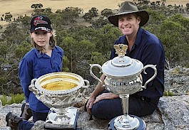 IMPRESSED: Natimuk farmer Carl Sudholz and his son Benson, 9, with the Daphne Akhurst Memorial Cup and Norman Brookes Challenge Cup atop Mt Arapiles with the Australian Open logo cut into a paddock in the background. Picture: TENNIS VICTORIA